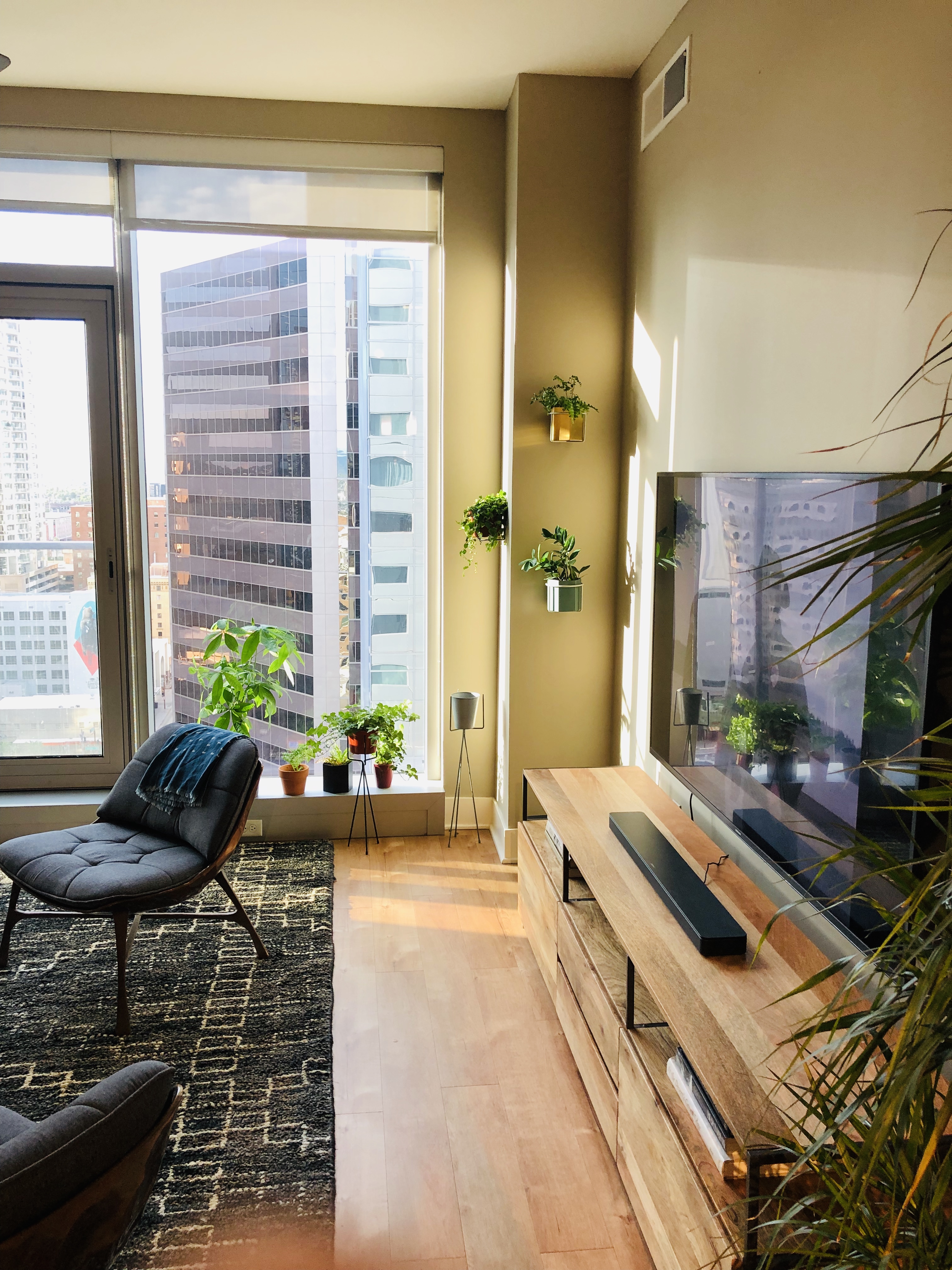 Modern apartment with city view, plants, and warm lighting