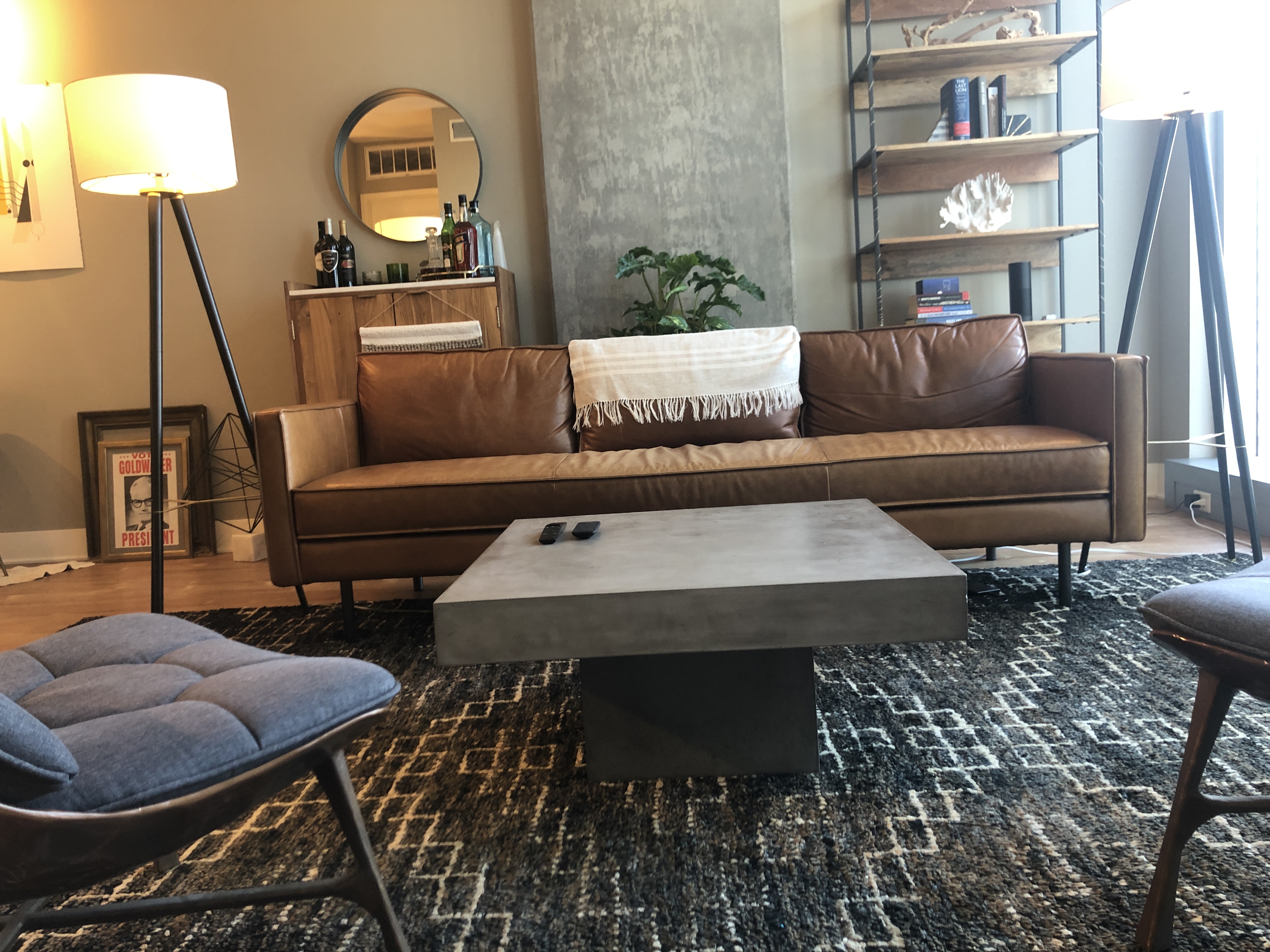 Well-designed male living room with leather couch, concrete coffee table, and balanced lighting
